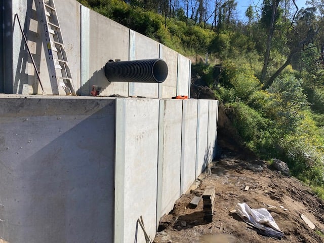 Concrete retaining wall with installed drainage pipe on Upper Brogo Road project by South East Civil & Crane.