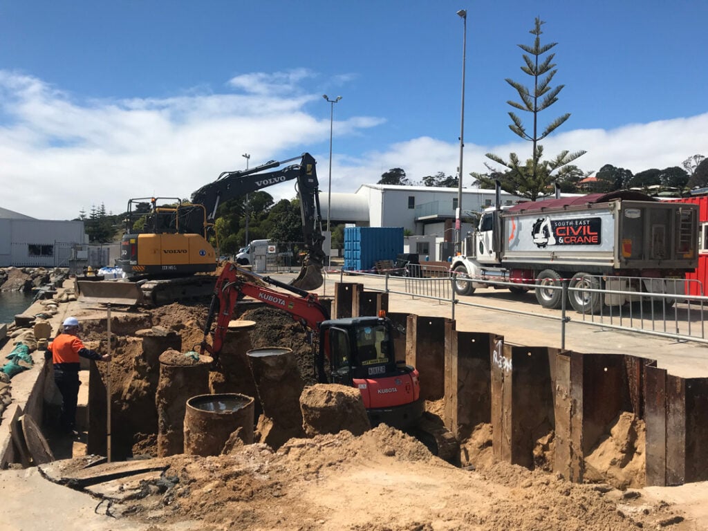 Excavators and trucks working on waterfront upgrade at Eden Breakwater Wharf by South East Civil & Crane.