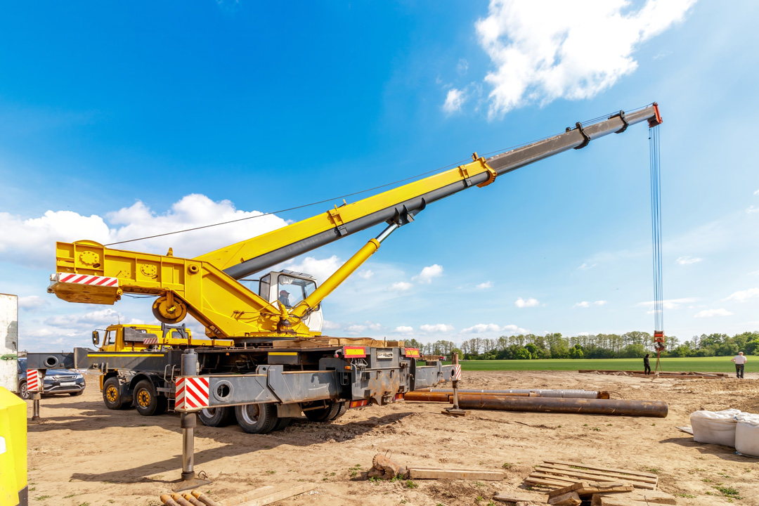 Telescopic crane lifting materials on open site operated by South East Civil & Crane.