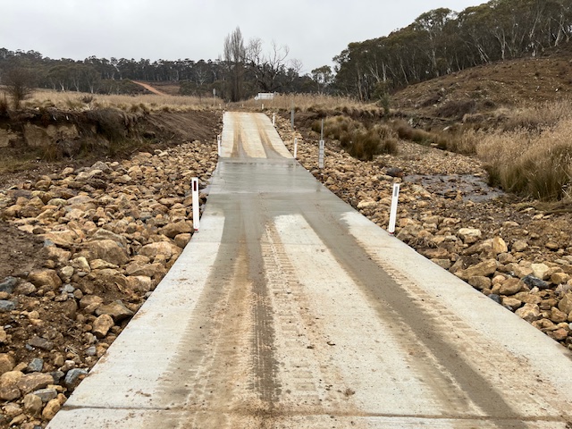 wet concrete causeway with muddy vehicle tracks at the new springs crossing